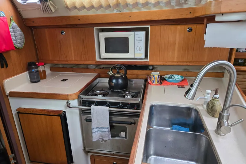 Slide: The Image of Compact kitchen in a 1999 Catalina 380 sailboat with stove, sink, and microwave. - 34
