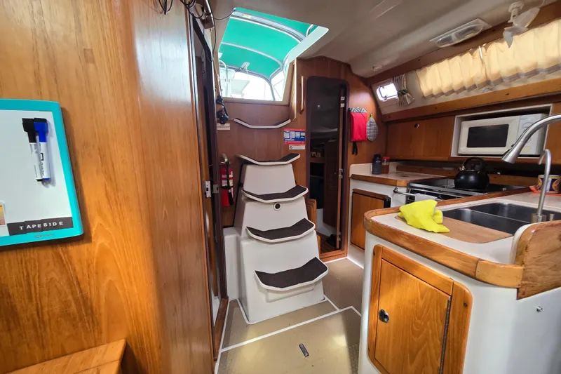 Slide: The Image of Interior of a 1999 Catalina 380 sailboat featuring a compact kitchen and wooden cabinetry. - 39