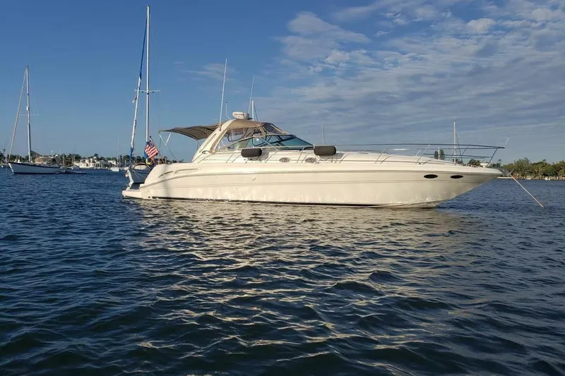 The Image of 2003 Sea Ray 410 Express Cruiser yacht anchored on calm water under a clear blue sky. - 0