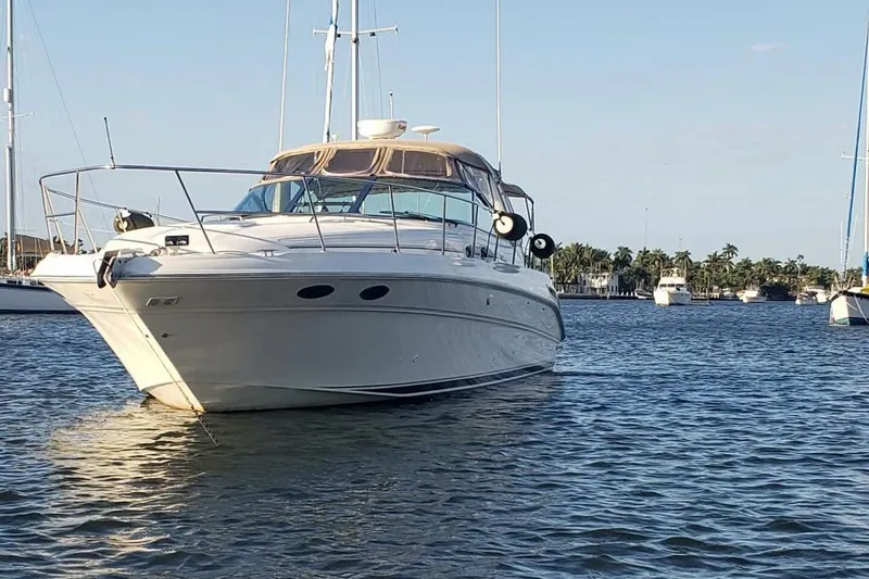 Slide: The Image of 2003 Sea Ray 410 Express Cruiser anchored on calm waters, surrounded by other boats. - 2