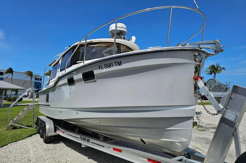 Slide: The Image of 2023 Ranger Tugs boat on trailer, parked outdoors under clear blue sky. - 2
