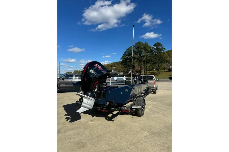Slide: The Image of 2026 Lund 1975 Renegade boat with powerful outboard motor, parked outdoors under clear blue sky. - 5