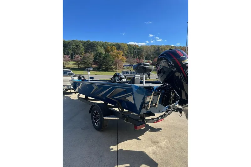 Slide: The Image of 2026 Lund 1975 Renegade boat on trailer, parked outdoors under clear blue sky. - 7