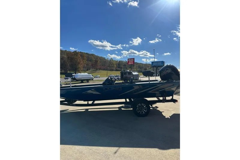 Slide: The Image of 2026 Lund 1975 Renegade boat parked outdoors under a clear blue sky. - 8