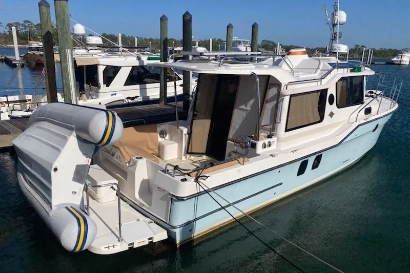 Slide: The Image of 2020 Ranger Tugs R-29 S docked at marina, featuring inflatable dinghy and spacious deck. - 4