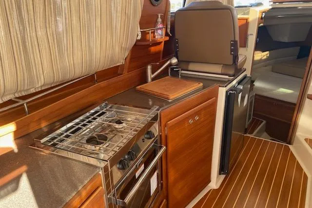 Slide: The Image of 2020 Ranger Tugs R-29 S interior kitchen with stove, sink, and wooden cabinetry. - 8