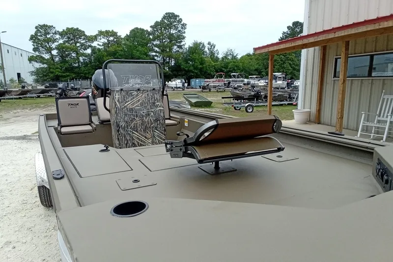 Slide: The Image of 2027 Thor 1900 Bay Hammer boat with camouflage seating, parked outdoors near a building. - 31