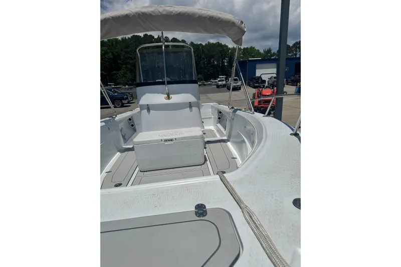 Slide: The Image of 2004 Triumph 210 CC boat interior with seating and canopy, parked outdoors. - 11