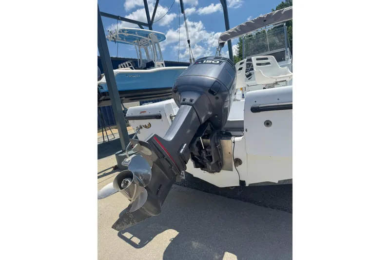 Slide: The Image of 2004 Triumph 210 CC boat with a 150 HP outboard motor, docked under blue skies. - 2