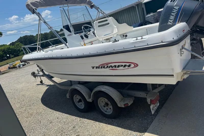Slide: The Image of 2004 Triumph 210 CC boat on trailer with Yamaha engine, parked outdoors. - 4