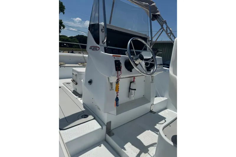 Slide: The Image of 2004 Triumph 210 CC boat console with steering wheel and controls under sunny sky. - 8