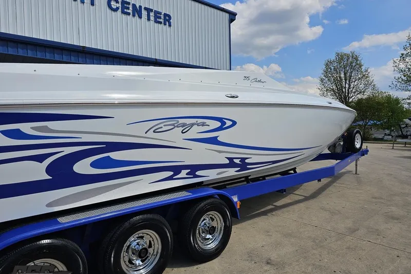 Slide: The Image of 2006 Baja 35 Outlaw boat on trailer with blue and white design, parked outdoors. - 10