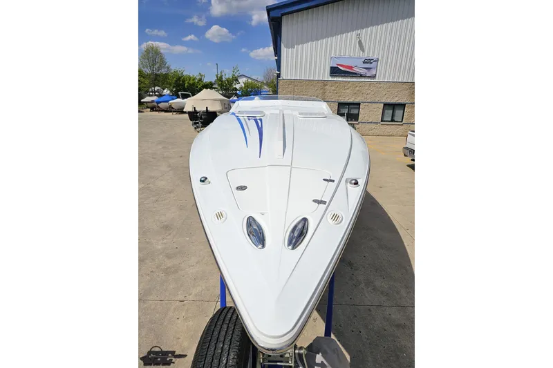 Slide: The Image of 2006 Baja 35 Outlaw boat with sleek white design and blue accents, parked outdoors. - 15