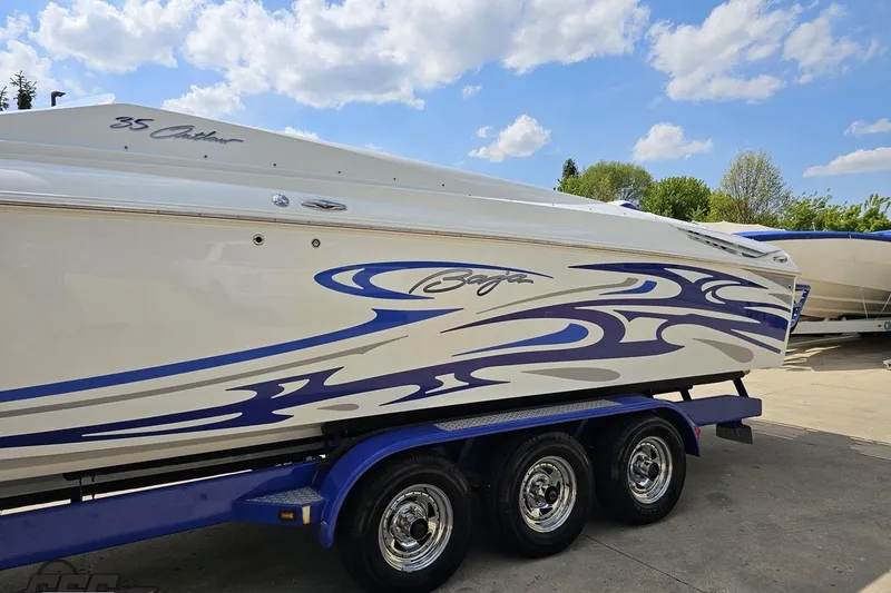 Slide: The Image of 2006 Baja 35 Outlaw boat with blue graphics on a trailer under a cloudy sky. - 19