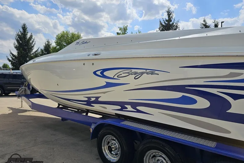 Slide: The Image of 2006 Baja 35 Outlaw boat with blue graphics on a trailer under a cloudy sky. - 22