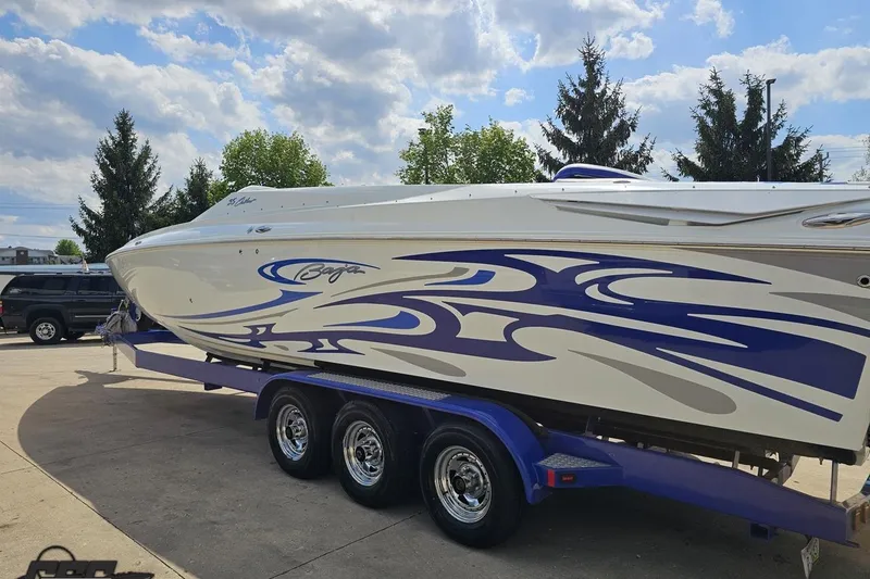 Slide: The Image of 2006 Baja 35 Outlaw boat with blue graphics on a trailer under a cloudy sky. - 24