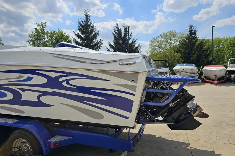 Slide: The Image of 2006 Baja 35 Outlaw boat with blue graphics on a trailer, parked outdoors. - 25