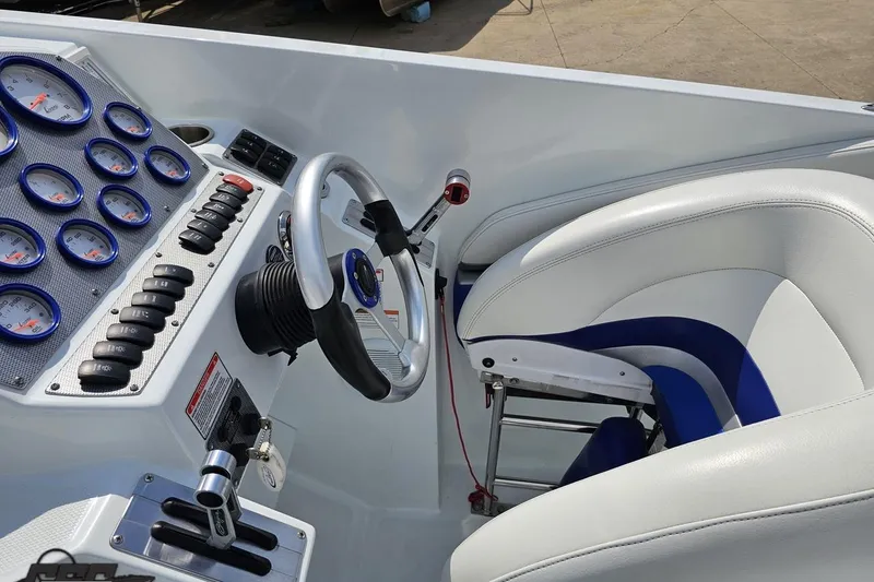 Slide: The Image of 2006 Baja 35 Outlaw boat cockpit with gauges, steering wheel, and white-blue seating. - 46