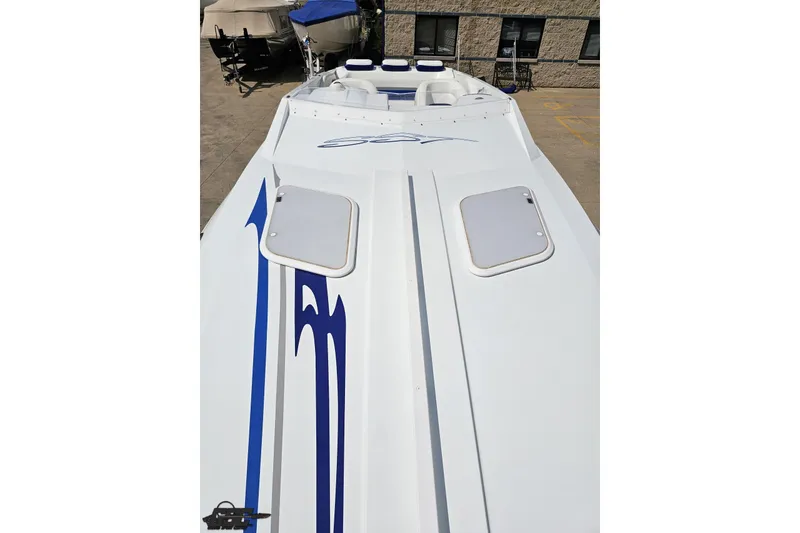 Slide: The Image of 2006 Baja 35 Outlaw boat with sleek white and blue design, docked outdoors. - 57