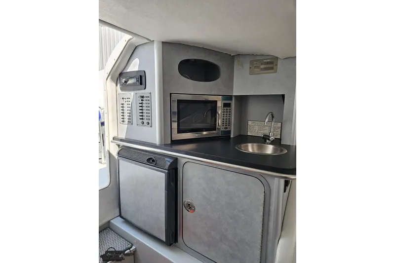 Slide: The Image of 2006 Baja 35 Outlaw boat interior with kitchenette, featuring microwave, sink, and storage. - 64