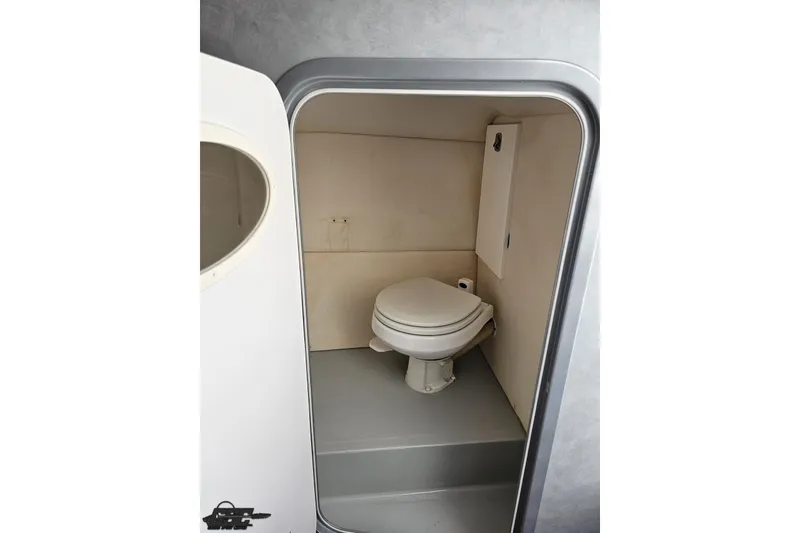Slide: The Image of Compact bathroom inside a 2006 Baja 35 Outlaw boat, featuring a toilet and minimalist design. - 74