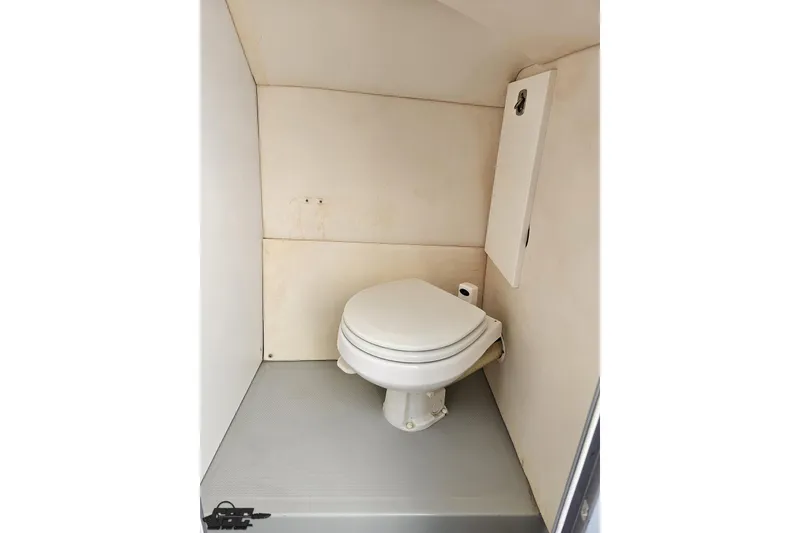 Slide: The Image of Compact bathroom in a 2006 Baja 35 Outlaw boat, featuring a white toilet. - 75