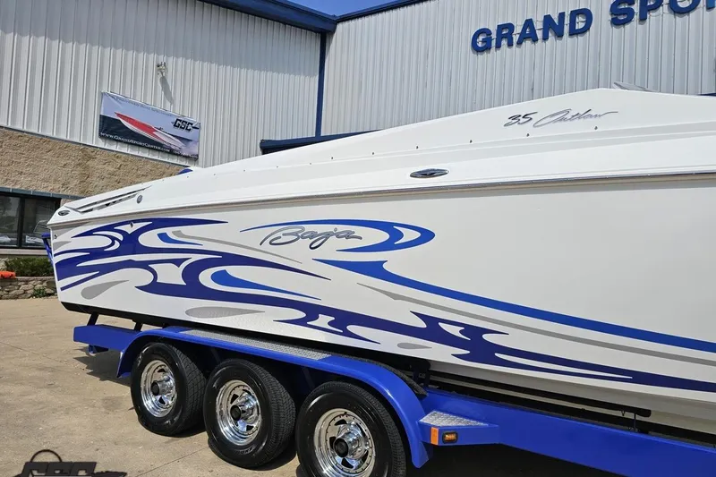 Slide: The Image of 2006 Baja 35 Outlaw boat with blue graphics on a trailer outside a dealership. - 8