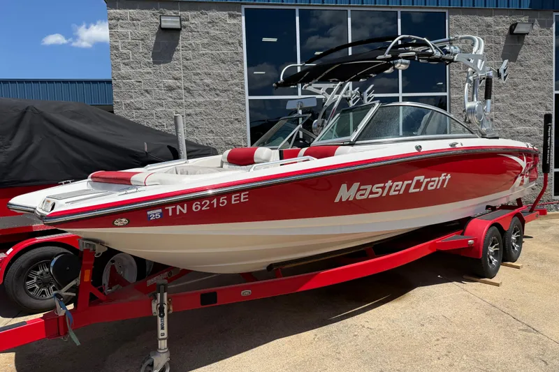 The Image of 2013 MasterCraft X-45 boat on red trailer, parked outside a building. - 0