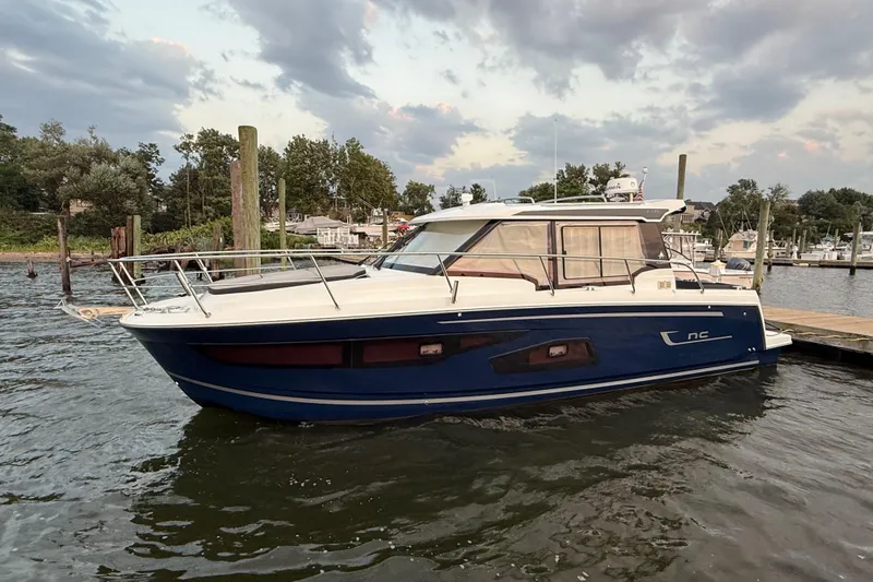 Slide: The Image of 2022 Jeanneau NC Weekender 1095 docked at a marina under a cloudy sky. - 2