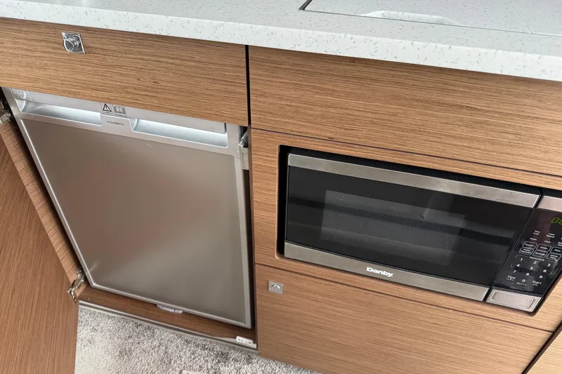 Slide: The Image of 2022 Jeanneau NC Weekender 1095 kitchen with microwave and fridge. - 4