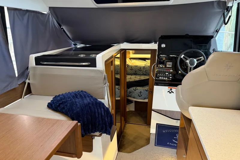 Slide: The Image of Interior of 2022 Jeanneau NC Weekender 1095, featuring helm, seating, and cozy cabin. - 5