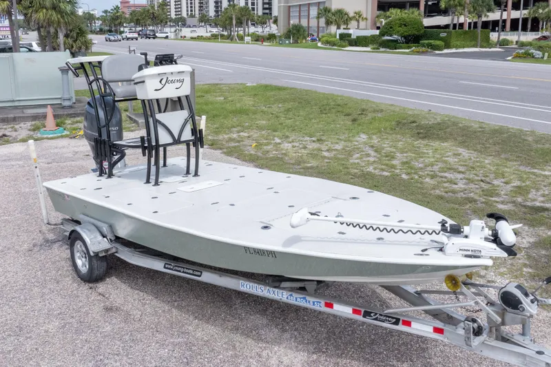 Slide: The Image of 2012 Young GulfShore 20 boat on trailer, parked near road with buildings in background. - 2