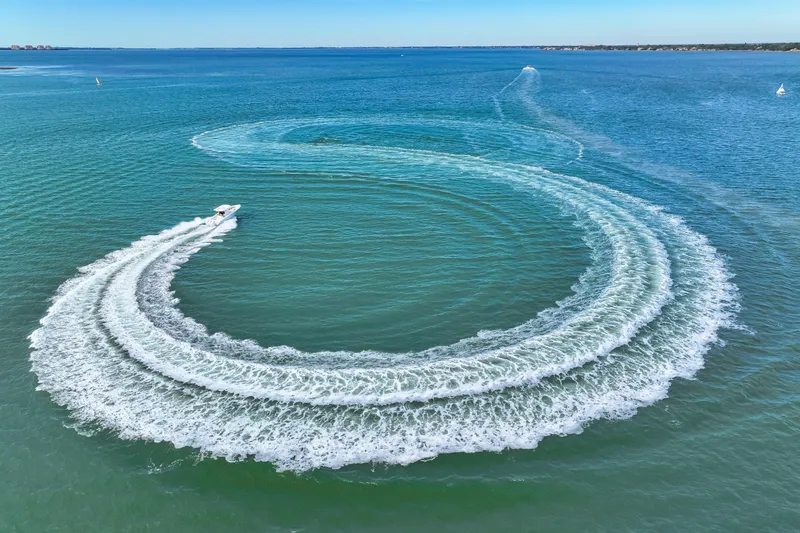 Slide: The Image of 2025 Jupiter 34 HFS boat creating circular wake pattern on open water. - 43
