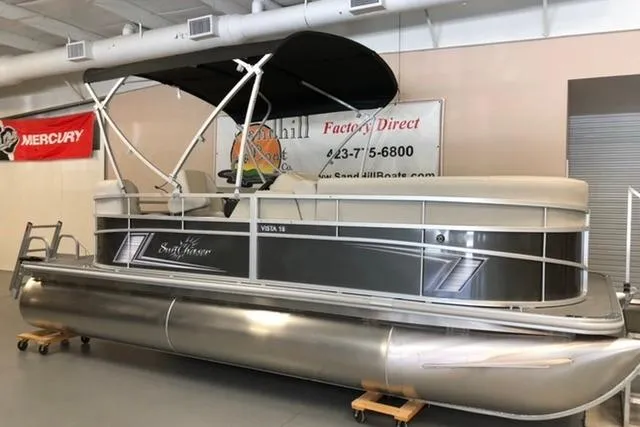 The Image of 2024 SunChaser Vista 18 LR pontoon boat displayed indoors with canopy. - 0