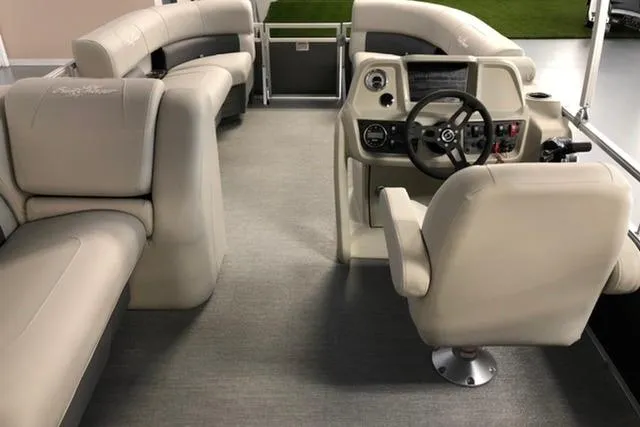 Slide: The Image of 2024 SunChaser Vista 18 LR pontoon boat interior with beige seating and modern helm. - 2