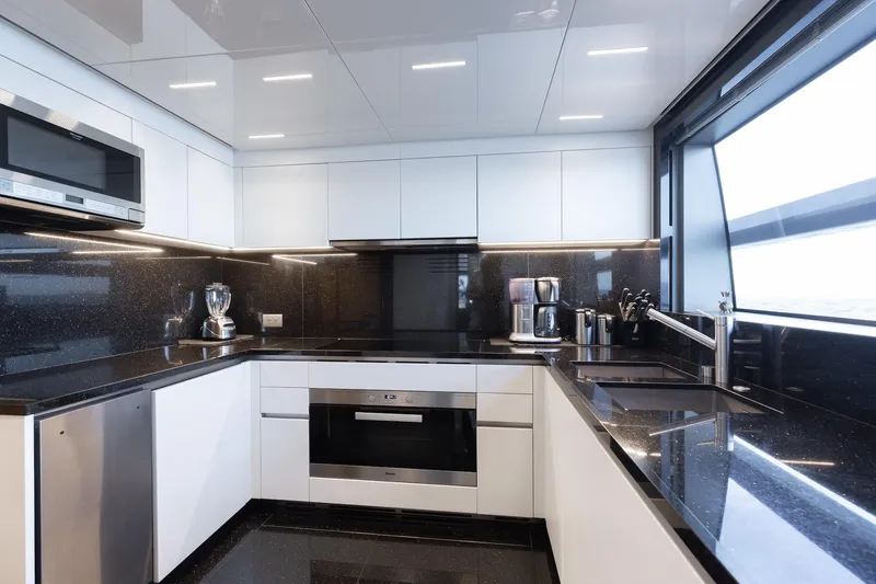 Slide: The Image of Modern kitchen interior on 2020 Sanlorenzo SLA120A yacht, featuring sleek black and white design. - 21