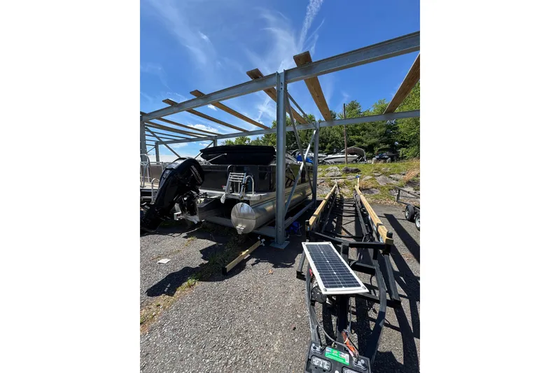 Slide: The Image of 2023 Crest CLASSIC LX FISH 200 C4 pontoon boat under metal frame, sunny day. - 3