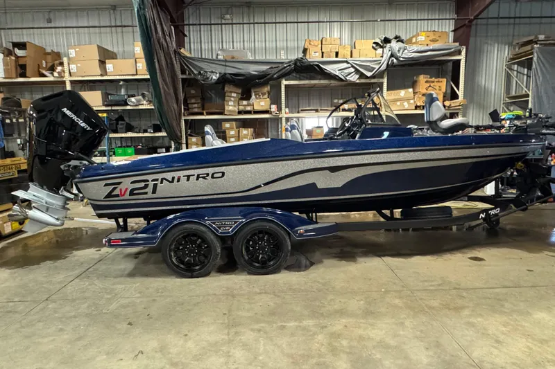 The Image of 2026 Nitro ZV21 Pro boat in warehouse, featuring Mercury engine and dual-axle trailer. - 0