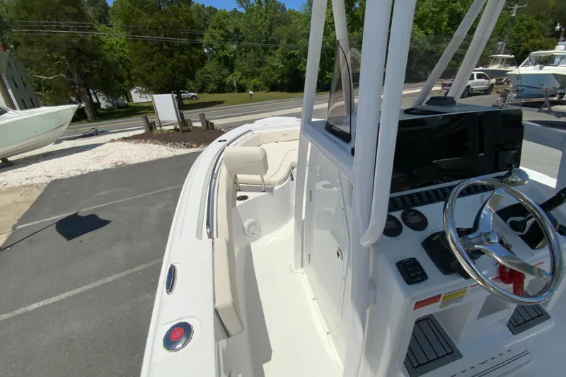 Slide: The Image of 2024 Sea Hunt Ultra 234 boat interior with steering wheel and seating, parked outdoors. - 21