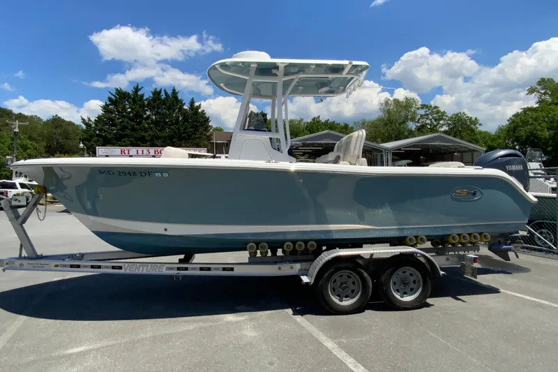 Slide: The Image of 2024 Sea Hunt Ultra 234 boat on trailer, parked outdoors under blue sky. - 6