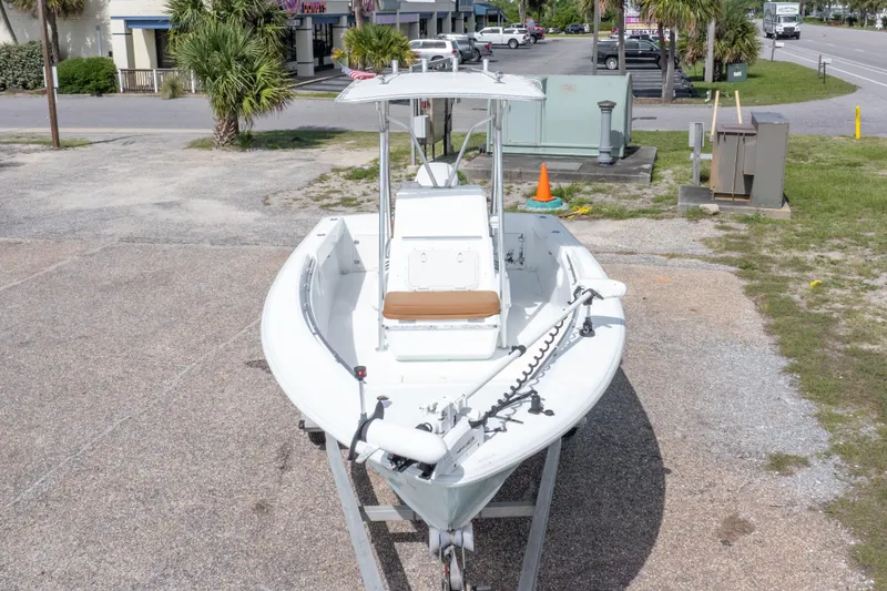 Slide: The Image of 1998 Contender 21 CC boat on trailer, parked outdoors near palm trees and buildings. - 10