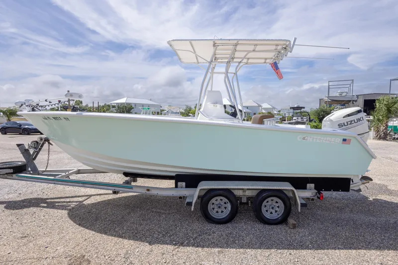 Slide: The Image of 1998 Contender 21 CC boat on trailer, featuring a Suzuki outboard motor, under a partly cloudy sky. - 11