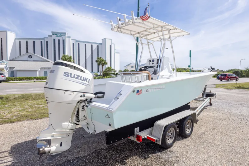 Slide: The Image of 1998 Contender 21 CC boat on trailer with Suzuki engine, parked near a hotel. - 13