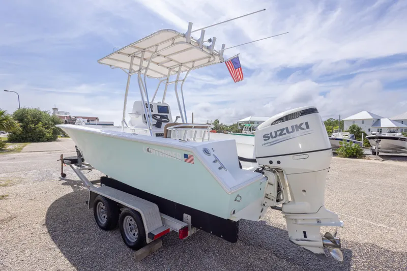 Slide: The Image of 1998 Contender 21 CC boat with Suzuki outboard motor on trailer, parked outdoors. - 16