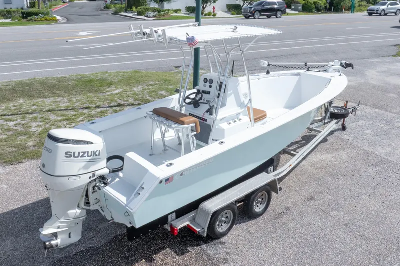 Slide: The Image of 1998 Contender 21 CC boat on trailer with Suzuki outboard motor, parked near road. - 17