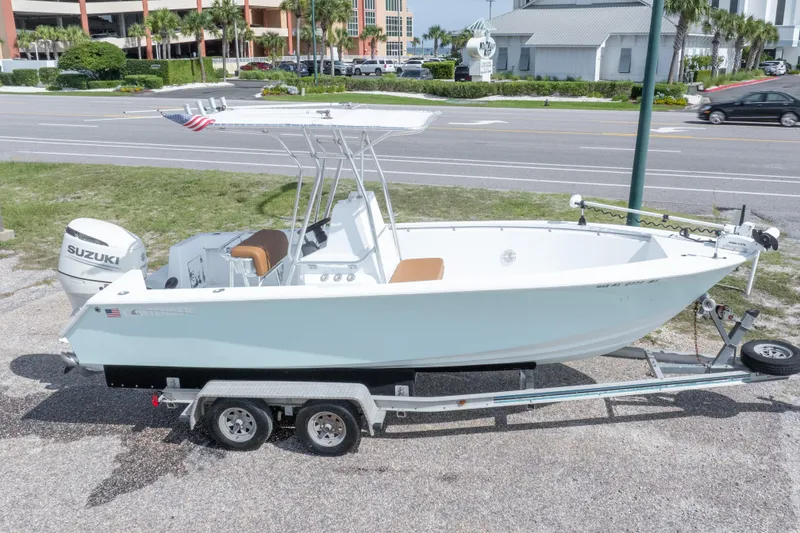Slide: The Image of 1998 Contender 21 CC boat on trailer with Suzuki outboard motor, parked roadside. - 2