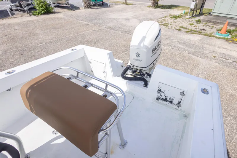 Slide: The Image of 1998 Contender 21 CC boat with Suzuki outboard motor and brown seat, parked on concrete. - 26