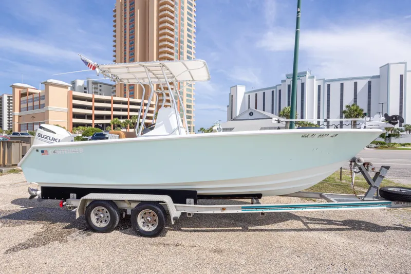 Slide: The Image of 1998 Contender 21 CC boat on trailer, parked near tall buildings under a clear sky. - 3