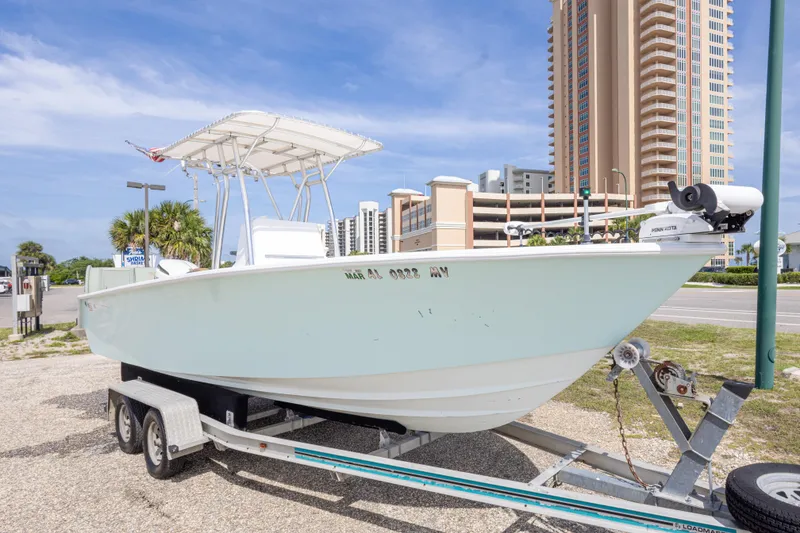 Slide: The Image of 1998 Contender 21 CC boat on trailer, parked near tall buildings under blue sky. - 5
