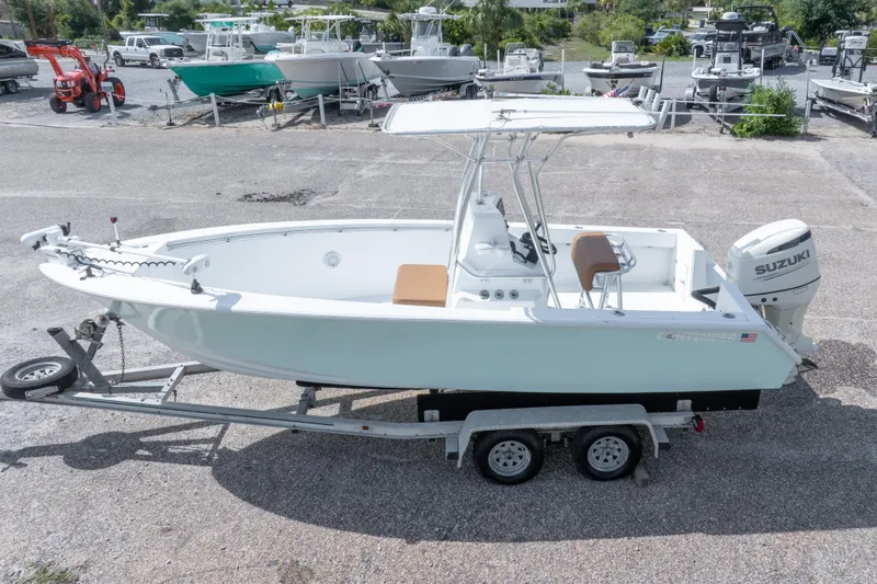 Slide: The Image of 1998 Contender 21 CC boat on trailer with Suzuki outboard motor, parked in a marina. - 9